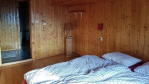 A wooden-paneled room with a bed, a lamp, and a small red box on the wall. - Wärschu by Interhome (Albinen)