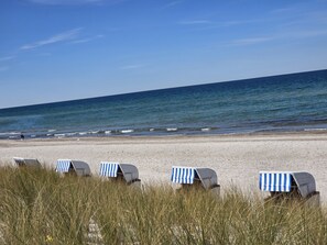 Beach chairs with striped awnings on a sandy beach with the ocean in the background. - Behagliches Ferienhaus mit Garten und Terrasse by Interhome (Rerik)