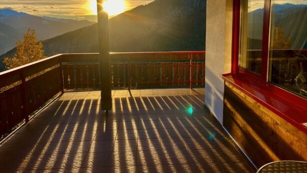 A balcony with a view of mountains and the sun setting. - Chalet Kristall by Interhome (Albinen)