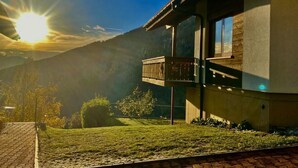 A modern house with a balcony overlooking a grassy yard and mountains. - Chalet Kristall by Interhome (Albinen)