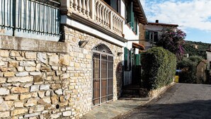 Un edificio de piedra con un balcón, una reja de metal y un camino adoquinado.