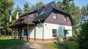 En toetages bygning med balkon, overdækket veranda og en lille have.