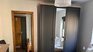 Et soveværelse med en træseng, et skab og et skrivebord.