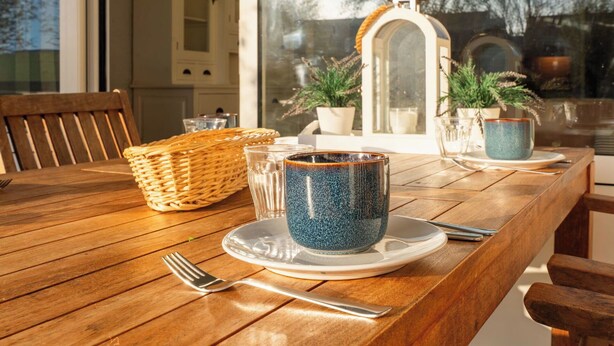 A wooden table with a ceramic mug, a glass, and a basket. - Lovely apartment for 4 guests with WIFI, pool, TV, terrace and pets allowed (Bruinisse)