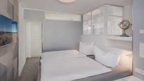 A modern bedroom with a large bed, a bedside table, a nightstand, a mirror, and a window with a decorative globe. - Stormy im Nauticum by Interhome (Ostseebad Lubmin)