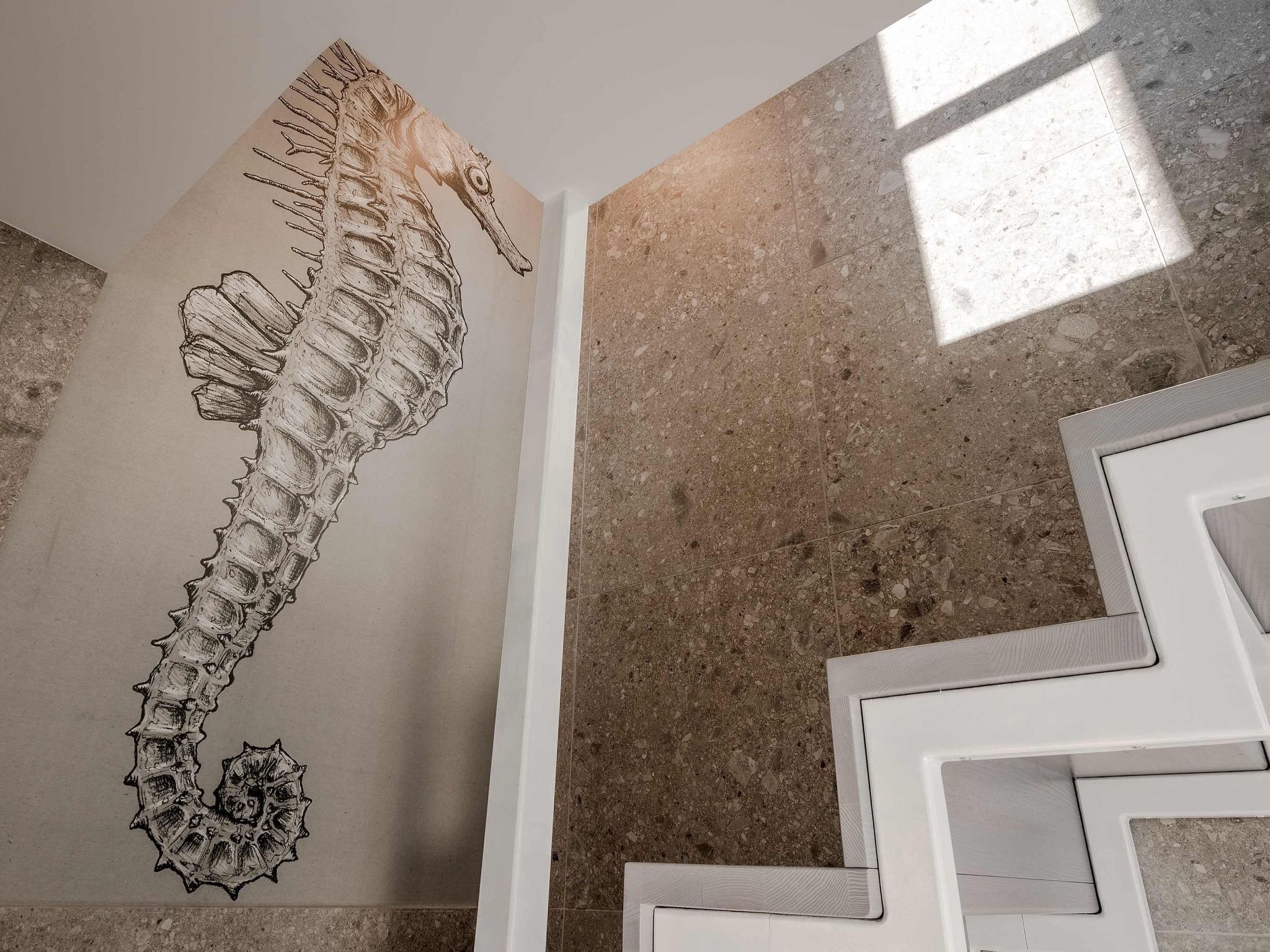Ein Seepferdchen-Wandgemälde, eine weiße Treppe und ein Terrazzo-Boden.