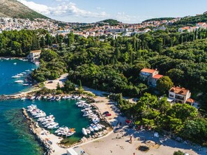 An aerial view of a coastal town with a marina, dense greenery, and buildings with red-tiled roofs. - Luxuriöse Villa am Strand in Dubrovnik mit Pool by Interhome (Dubrovnik)
