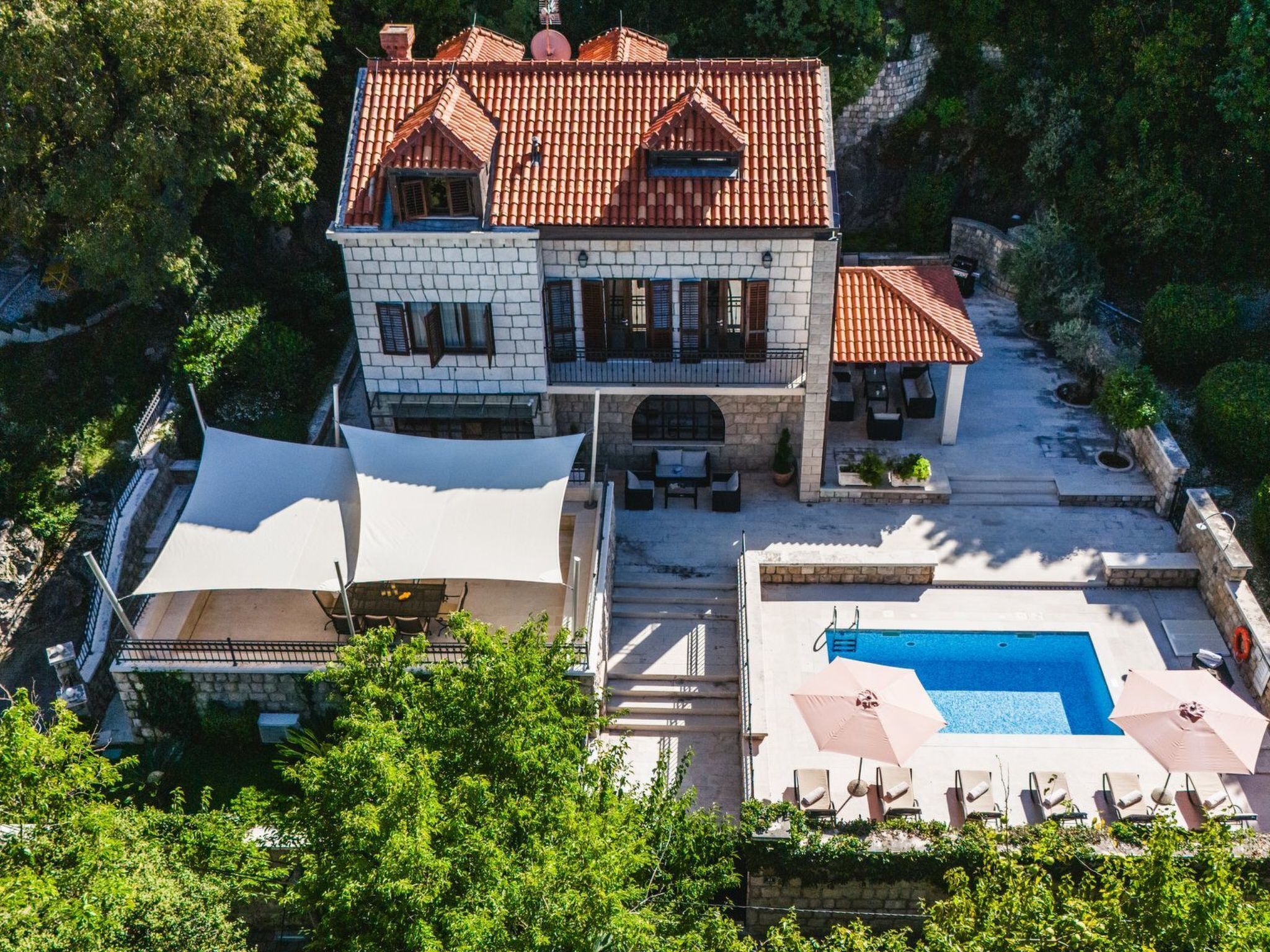 A two-story house with a swimming pool, outdoor seating, and a garden.