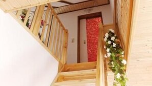 Eine Holztreppe, oben ist eine Wand mit roten Blumen zu sehen.