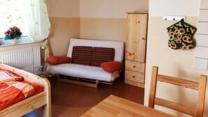Ein Schlafzimmer mit einem Bett, einem Holzstuhl, einem Heizkörper, einem Fenster mit Vorhängen und einer Wanddekoration.