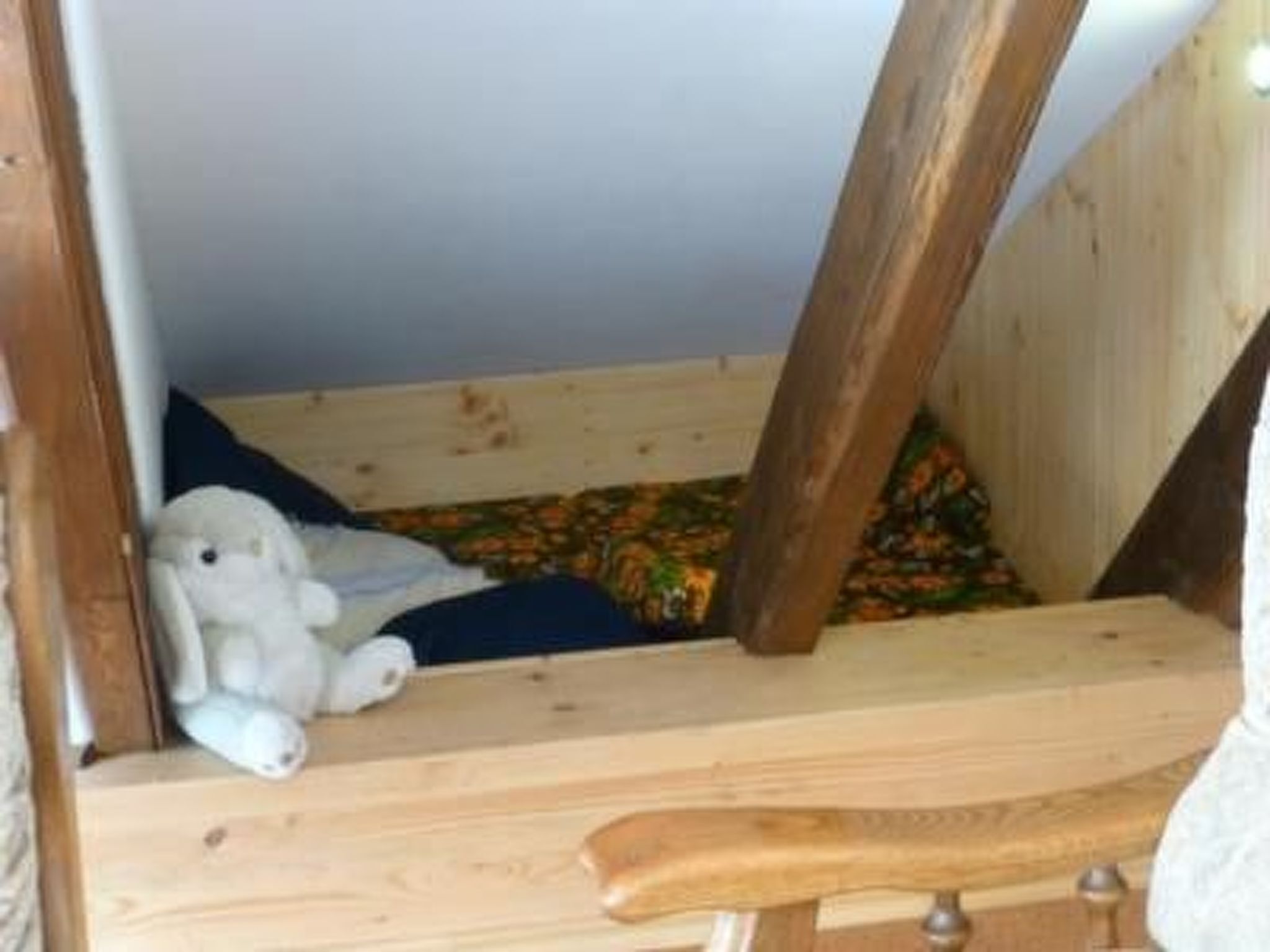 A wooden loft bed with a small seating area underneath.