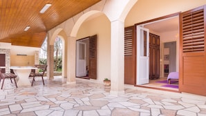 A covered patio area with a stone floor, wooden ceiling, and arched columns. - Carpe Diem by Interhome (Trogir)