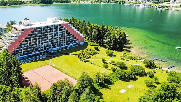 Ein Hotel mit modernem Design, einem Tennisplatz und Seeblick.