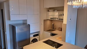 Eine moderne Küche mit Edelstahlgeräten, einer eingebauten Waschmaschine und einer kompakten Spüle.