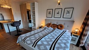 Ein modernes Schlafzimmer mit Bett, Nachttischen, einem Schreibtisch und einem Kleiderschrank.