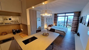 Ein modernes Hotelzimmer mit Küchenzeile, Essbereich und einem Balkon mit Blick.