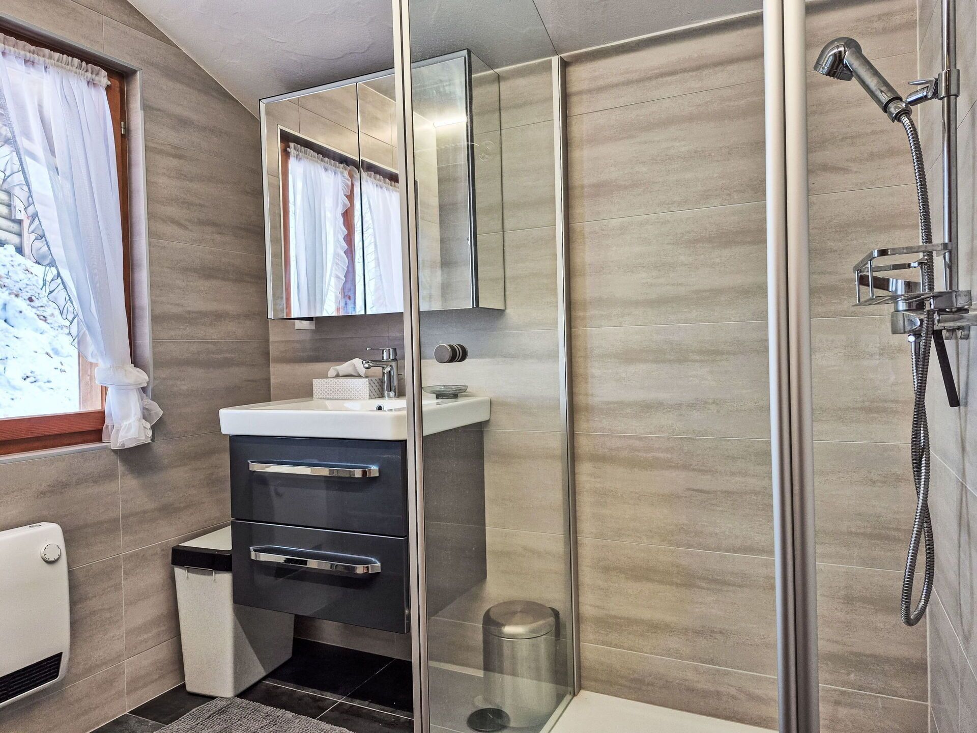 A modern bathroom with a glass shower enclosure, a sink with a mirror above, and a toilet.