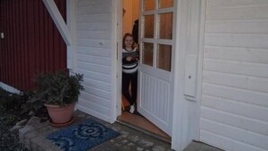 A white door with a glass panel, a potted plant, and a blue rug on the porch.
