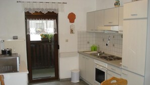 Une cuisine compacte équipée d’un réfrigérateur, d’une cuisinière, d’un évier et d’un coin repas avec une table et des chaises.