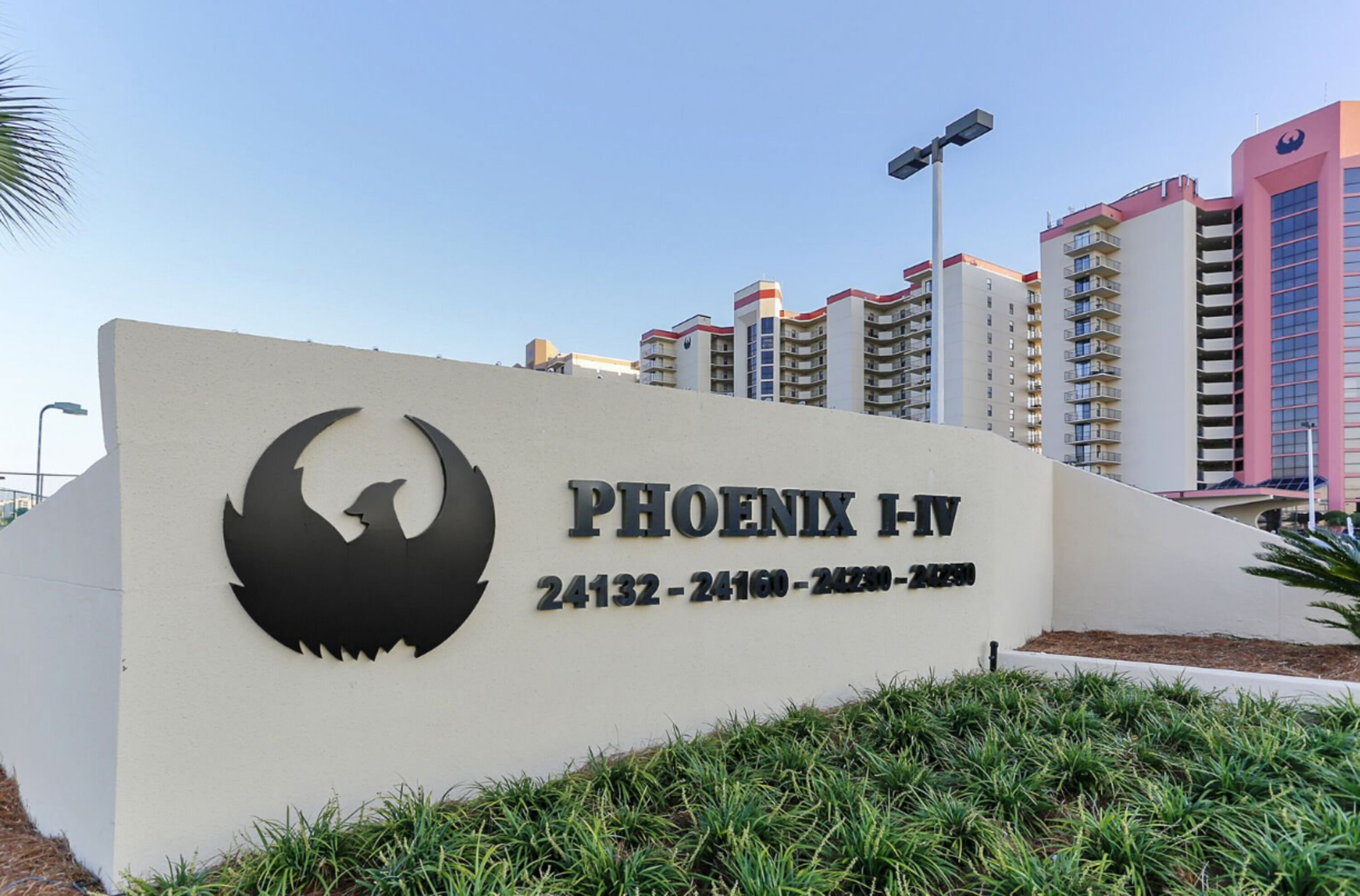 A sign for Phoenix I-IV with a bird logo, surrounded by modern buildings.