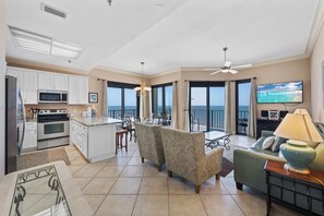 A spacious living area with a kitchen, dining area, and a balcony with a TV. - Phoenix III 3159 (Orange Beach)