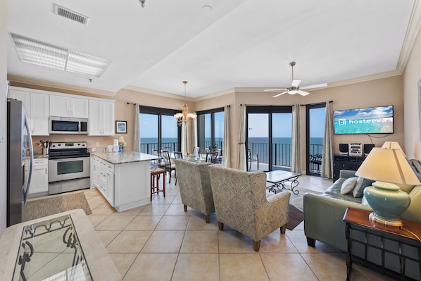 A spacious living area with a kitchen, dining area, and a balcony with a TV. - Phoenix III 3159 (Orange Beach)