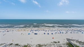 Una playa con numerosos paraguas y un muelle de madera.