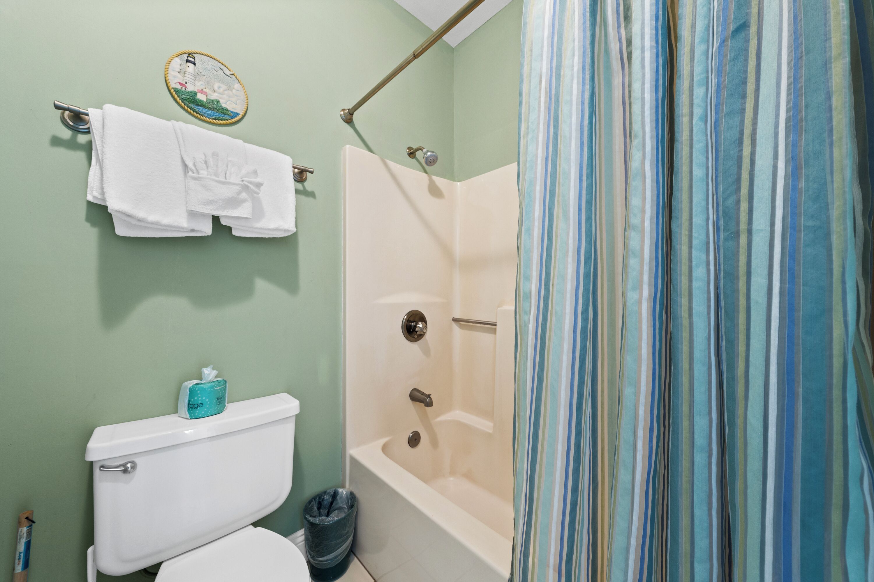 Un baño con inodoro, bañera, cortina de ducha y toallero.