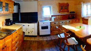 Une cuisine rustique avec des meubles en bois, un poêle et un coin repas comprenant une table et des chaises.
