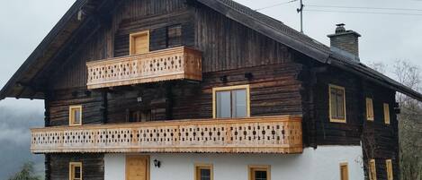 A two-story wooden house with a balcony and a chimney.
