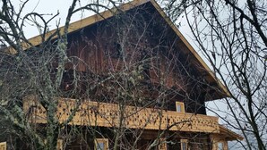 Une cabane en bois dotée d’un balcon, d’un escalier menant à l’étage supérieur et d’une fenêtre avec un cadre en bois.