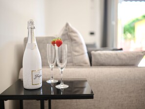 Eine Flasche Freikönig Ice Champagner, zwei Gläser und eine Erdbeere auf einem Tisch in einem Wohnzimmer mit Sofa und Fenster.