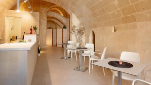 Un interior moderno con un arco de piedra, un mostrador de recepción y sillas blancas alrededor de una mesa.