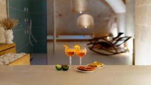 Un interior moderno con una zona de comedor que incluye dos cócteles, un plato de comida y una silla decorativa.