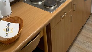 Een keuken met houten kastjes, twee roestvrijstalen spoelbakken, een gasfornuis en een mand met een etiket.