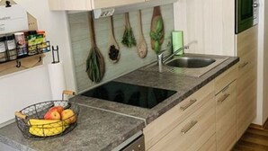 Une cuisine moderne avec des meubles de couleur bois clair, un évier à deux bacs et un lave-vaisselle.