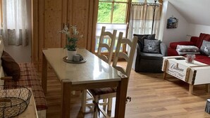 Une pièce chaleureuse avec une table à manger en bois, des chaises, un canapé et une fenêtre avec des rideaux.