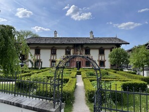 A historic building with a symmetrical facade, a central entrance, and a formal garden with a geometric hedge maze. - Baumberger by Interhome (Oberammergau)
