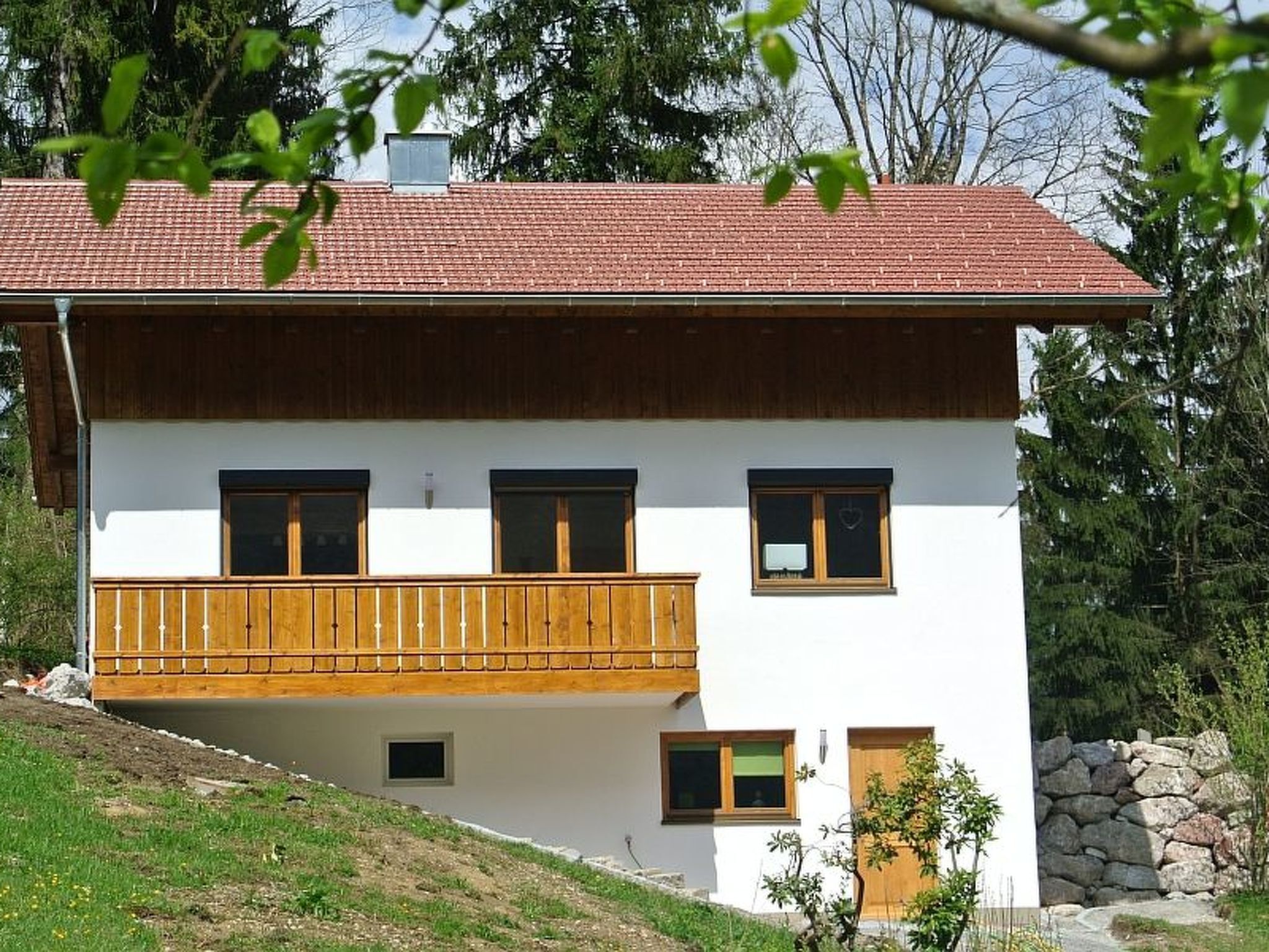 A two-story house with a balcony, white walls, and a red roof.
