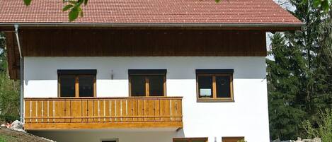 A two-story house with a balcony, white walls, and a red roof.