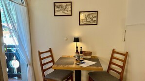 En matplats med två trästolar, ett bord, två inramade tavlor, en lampa och två ölflaskor.