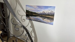 Ett fotografi som föreställer ett bergigt landskap med en sjö, och som hänger på en vägg.