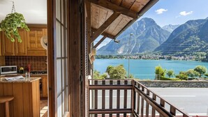Een houten interieur met een keuken, een balkon met uitzicht op een meer en bergen.