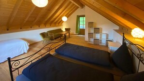 Um quarto de sótão aconchegante com teto inclinado, uma cama, um sofá e uma pequena mesa.