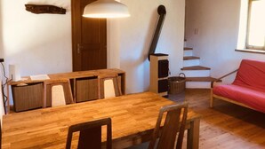 Uma mesa de jantar de madeira com cadeiras, um sofá vermelho, uma escada e uma lareira.