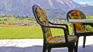 Twee stoelen met kleurrijke bloemenstoffering, gericht op een prachtig uitzicht op de bergen.