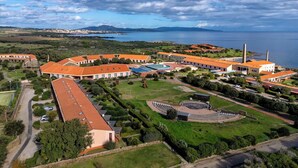 Eine Luftaufnahme eines Küstenresorts mit mehreren Gebäuden, einem Schwimmbad und einem großen Amphitheater.