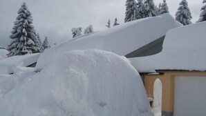 Paisagem coberta de neve com um edifício parcialmente escondido pela neve.