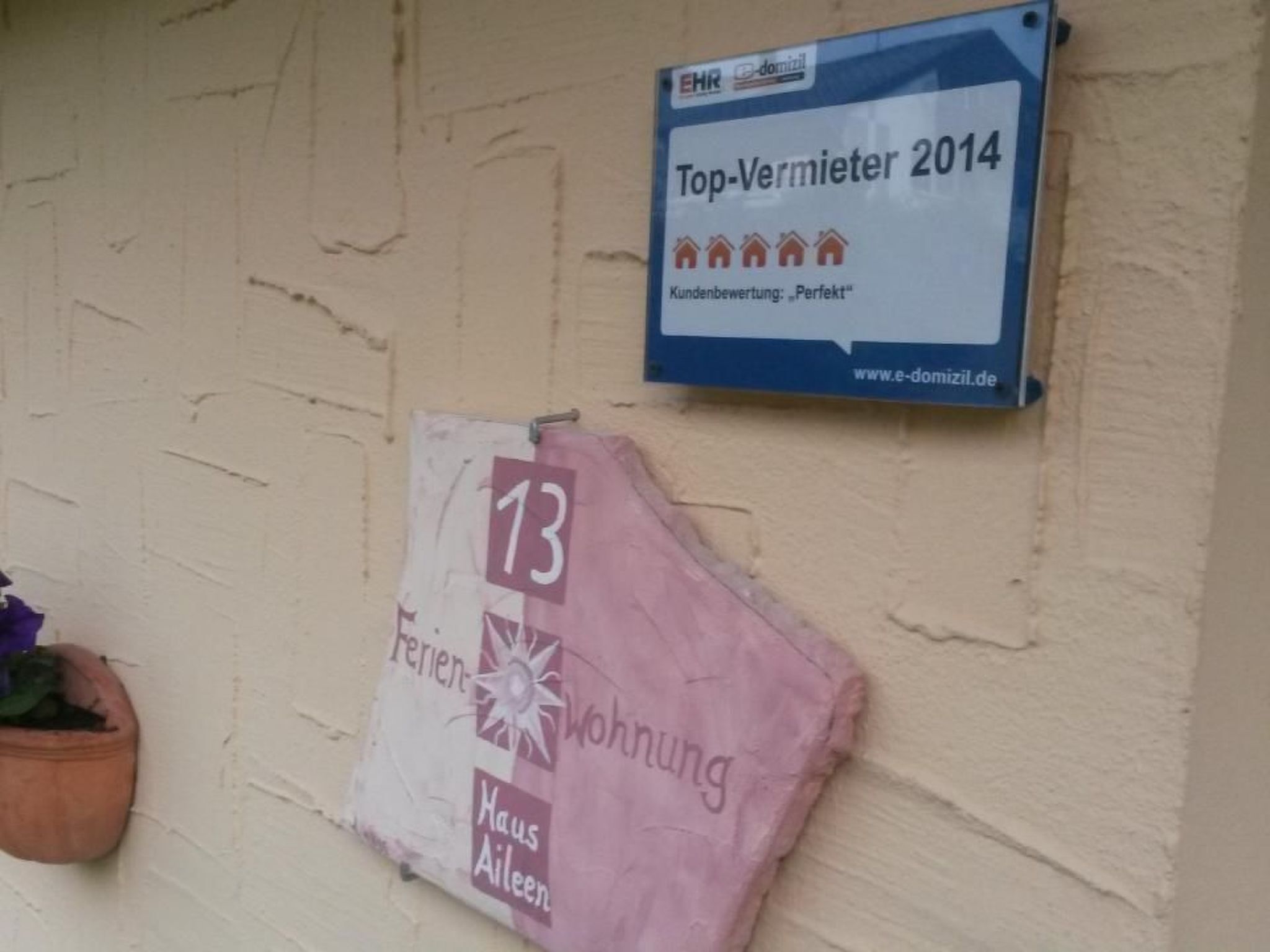 A sign for 'Top-Vermieter 2014' with a customer rating of 'Perfekt' and a website URL.