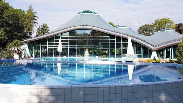Ein modernes Gebäude mit einer großen Glasfassade und einem Pool davor.